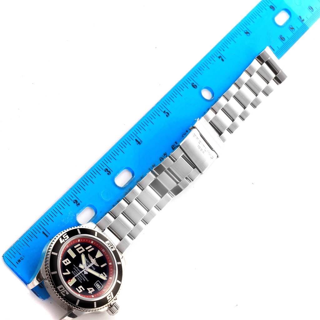 The image shows the face and metal bracelet of the Breitling Superocean A17364 Men's Stainless Steel Black Dial A17364 Men's Stainless Steel Black Dial watch, laid out flat beside a blue ruler.