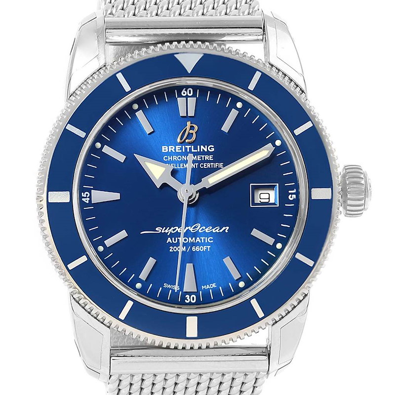 The image shows a frontal view of a Breitling Superocean watch, highlighting its blue dial, date window, bezel, and mesh bracelet.