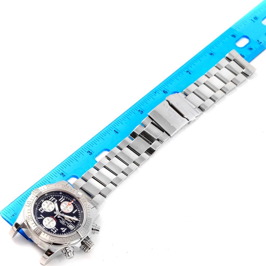 The Breitling Avenger A13381 Men's Stainless Steel Black Dial A13381 Men's Stainless Steel Black Dial watch is shown laying flat with its face, bracelet, and clasp visible next to a blue ruler.