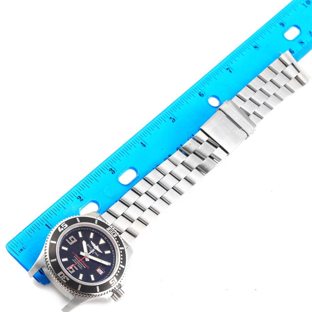 The image shows a Breitling Superocean A17391 Men's Stainless Steel Black Dial A17391 Men's Stainless Steel Black Dial watch laid flat next to a blue ruler, displaying its face and metal bracelet.