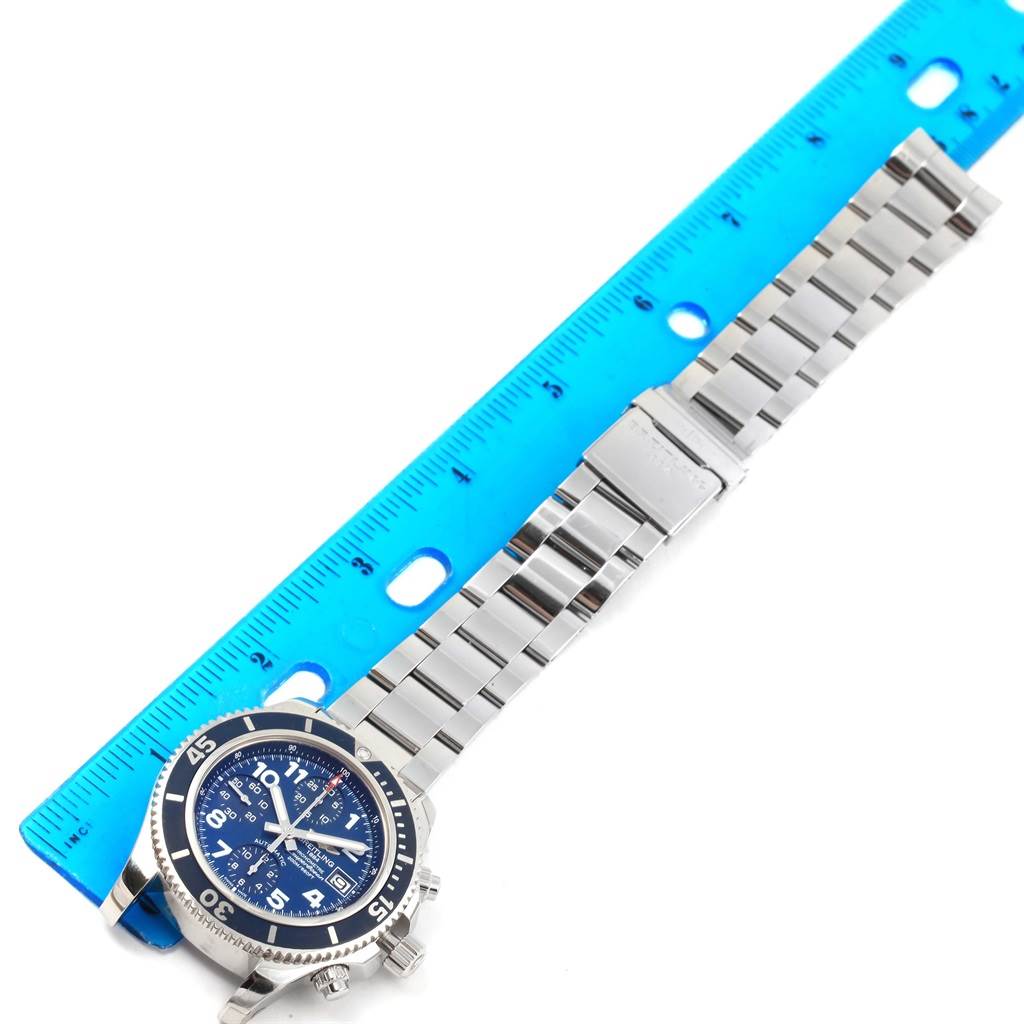 The Breitling Superocean A13311 Men's Stainless Steel Blue Dial A13311 Men's Stainless Steel Blue Dial watch is shown from an overhead angle with a blue dial and stainless steel bracelet next to a blue ruler.