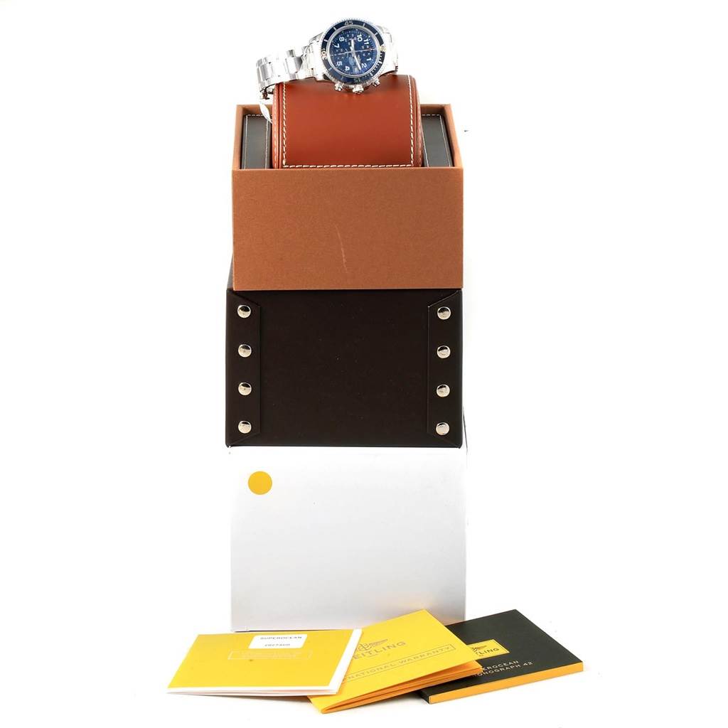 The image shows a Breitling Superocean A13311 Men
s Stainless Steel Blue Dial A13311 Men
s Stainless Steel Blue Dial watch resting on a leather case, accompanied by its packaging and manuals.