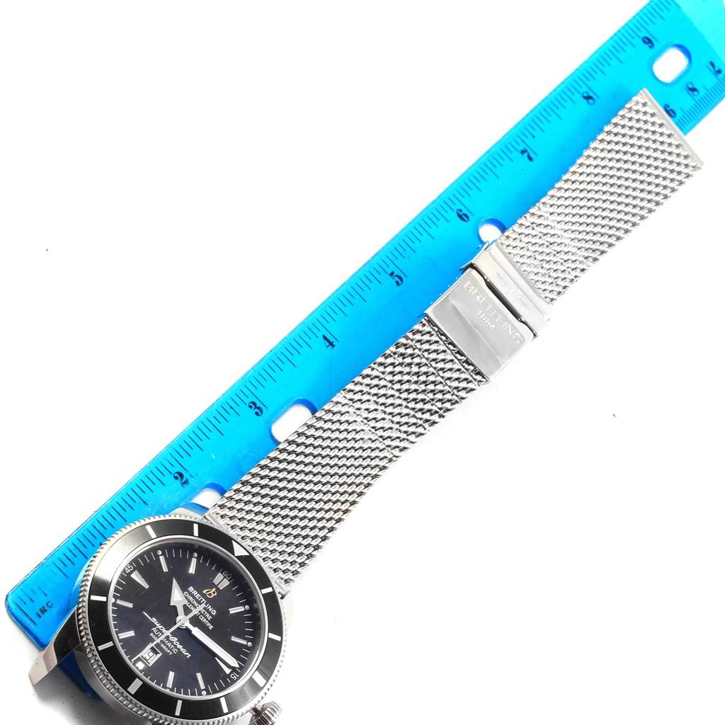 The image shows a Breitling Superocean A17320 Men's Stainless Steel Black Dial A17320 Men's Stainless Steel Black Dial watch placed next to a ruler, displaying its mesh bracelet and clasp from a top-down angle.