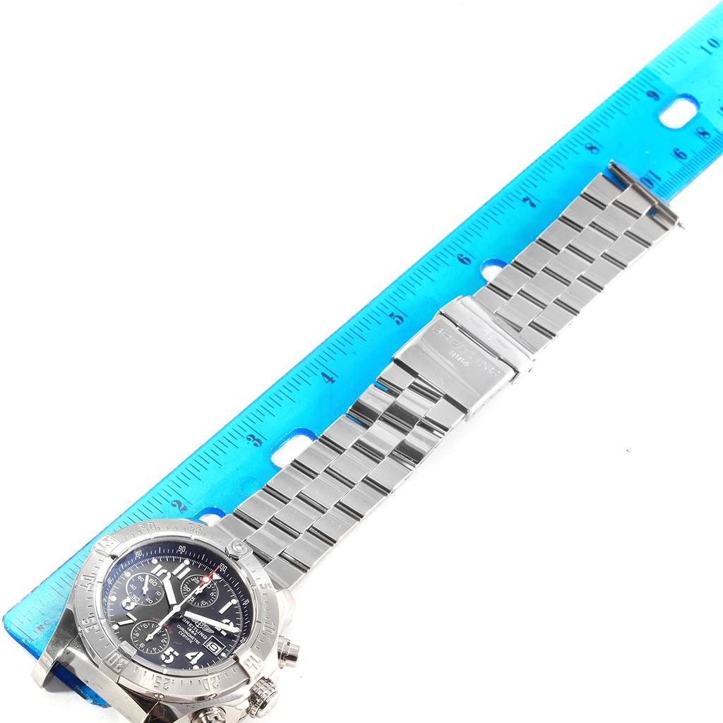 The Breitling Avenger A13380 Men's Stainless Steel Black Dial A13380 Men's Stainless Steel Black Dial watch is shown from an overhead angle, featuring its face and metal bracelet next to a blue ruler.