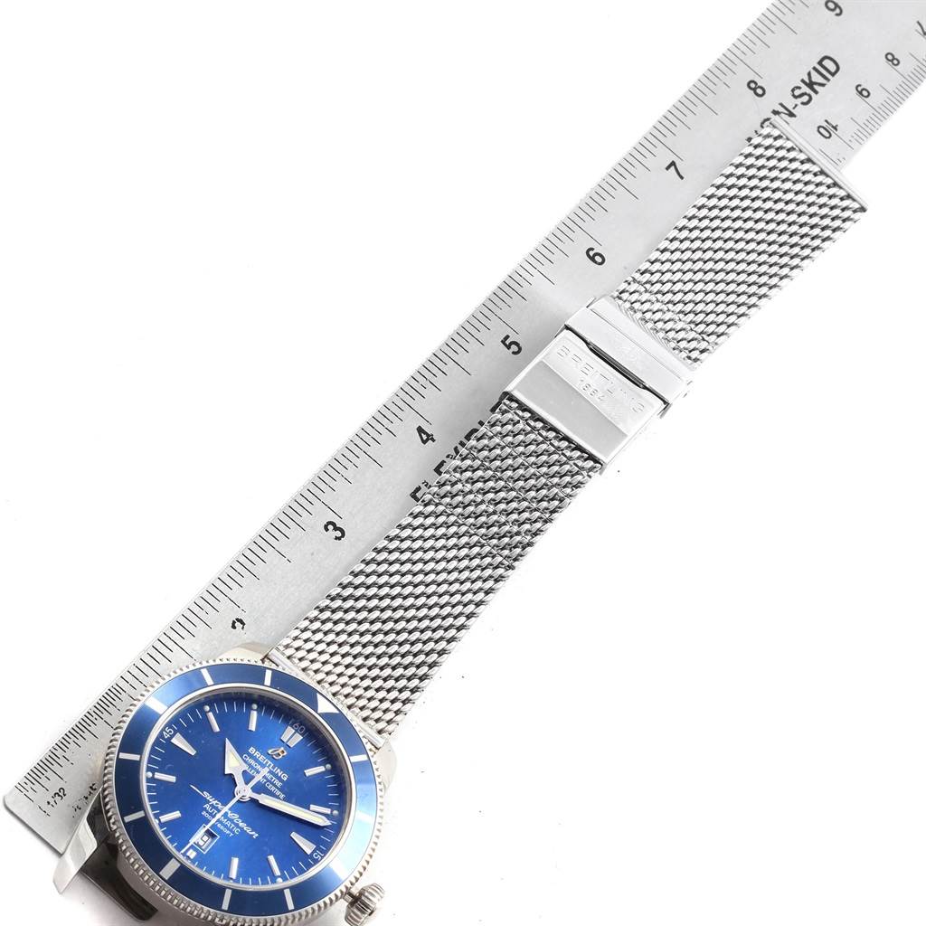 The image shows a top view of a Breitling Superocean A17320 Men's Stainless Steel Blue Dial A17320 Men's Stainless Steel Blue Dial watch, displaying its blue dial, mesh strap, and clasp, alongside a ruler.