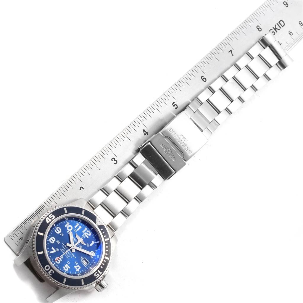 The image shows an overhead view of a Breitling Superocean A17392D8/C910 Men's Stainless Steel Blue Dial A17392D8/C910 Men's Stainless Steel Blue Dial watch with a blue dial, stainless steel bracelet, and adjacent ruler.