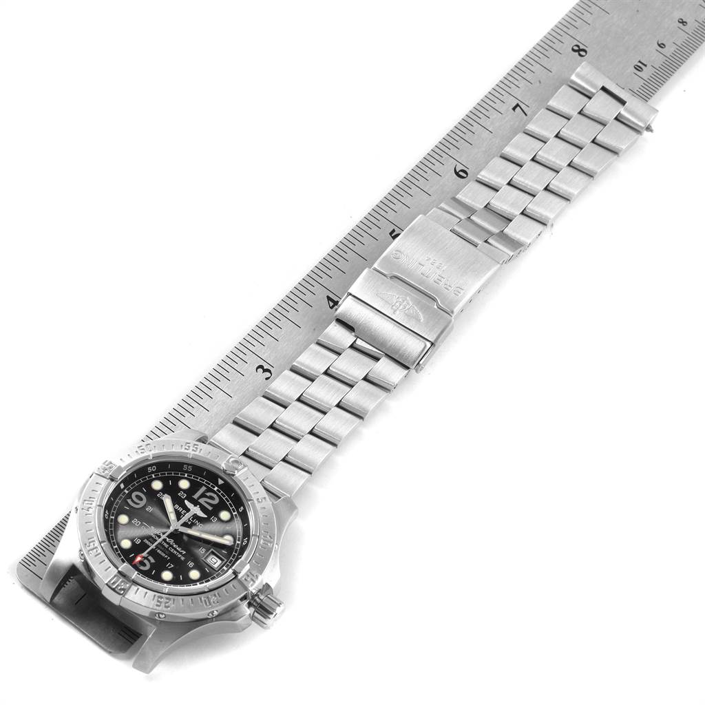 The image shows a top-down view of a Breitling Superocean A17390 Men's Stainless Steel Black Dial A17390 Men's Stainless Steel Black Dial watch, including its face and metal bracelet, alongside a ruler.