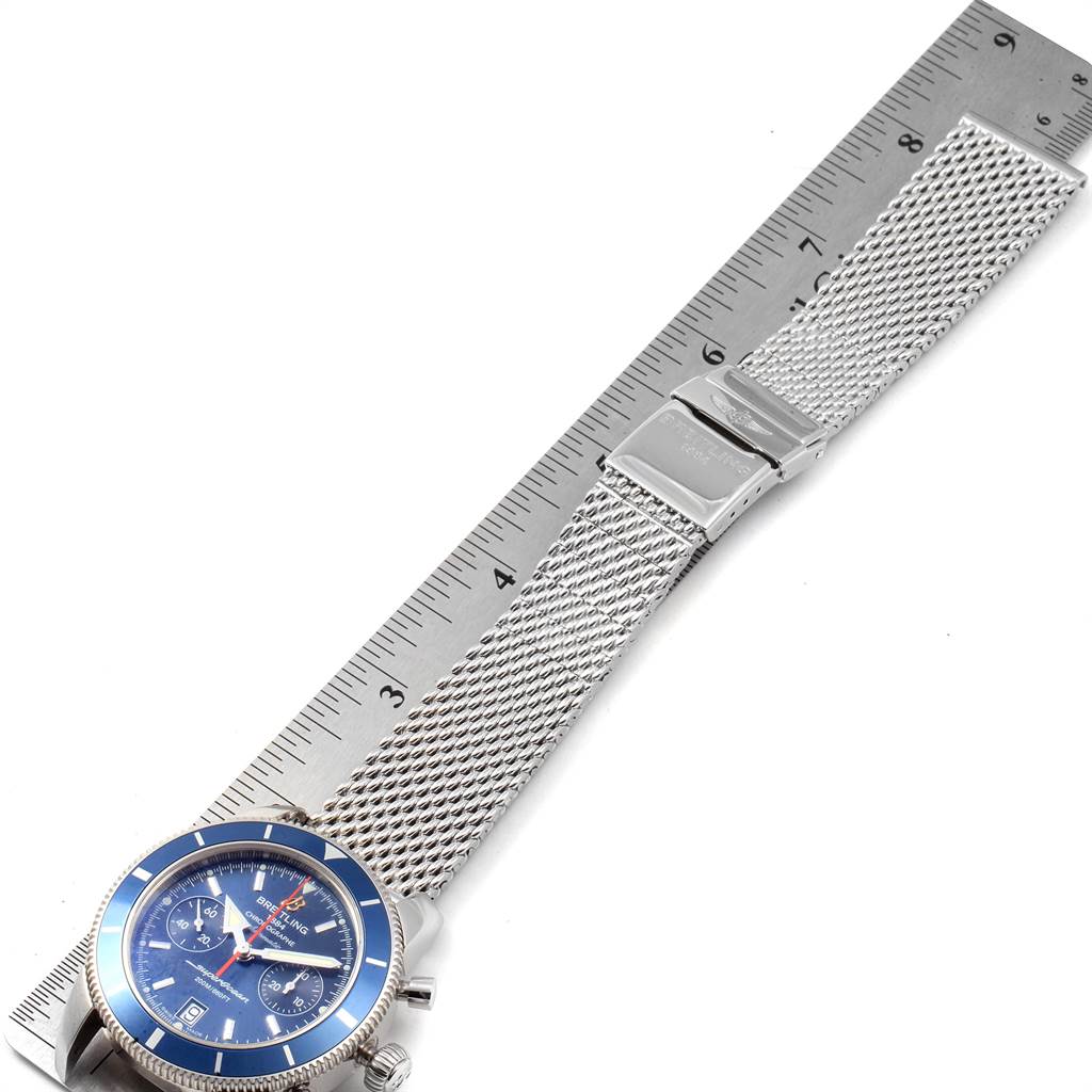The image shows a top-down view of a Breitling Superocean A2337 Men
s Stainless Steel Blue Dial A2337 Men
s Stainless Steel Blue Dial watch, highlighting its mesh bracelet and clasp alongside a ruler.