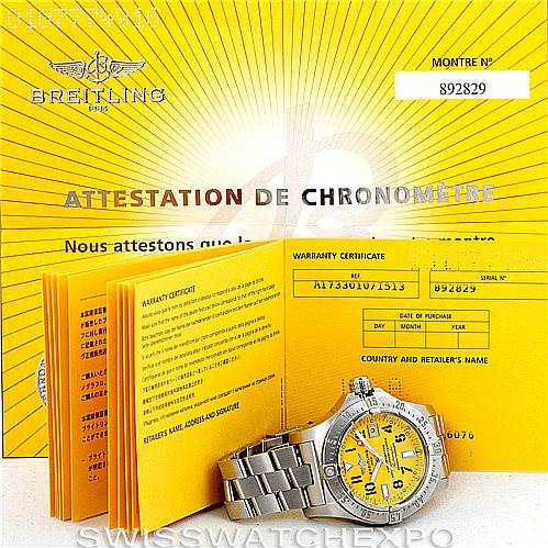 The Breitling Avenger A17330 Men's Stainless Steel Yellow Dial A17330 Men's Stainless Steel Yellow Dial watch is shown at a front angle with its warranty certificate and manual in the background.