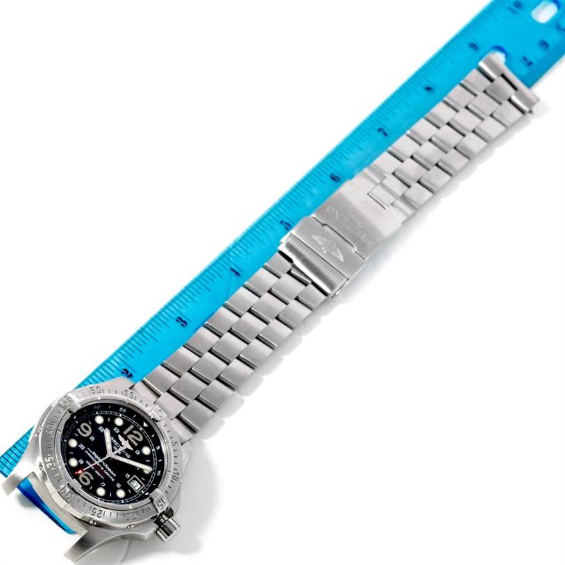 A Breitling Superocean A17390 Men's Stainless Steel Black Dial A17390 Men's Stainless Steel Black Dial watch is shown from a top-down angle, displaying its face and metal strap next to a blue ruler.