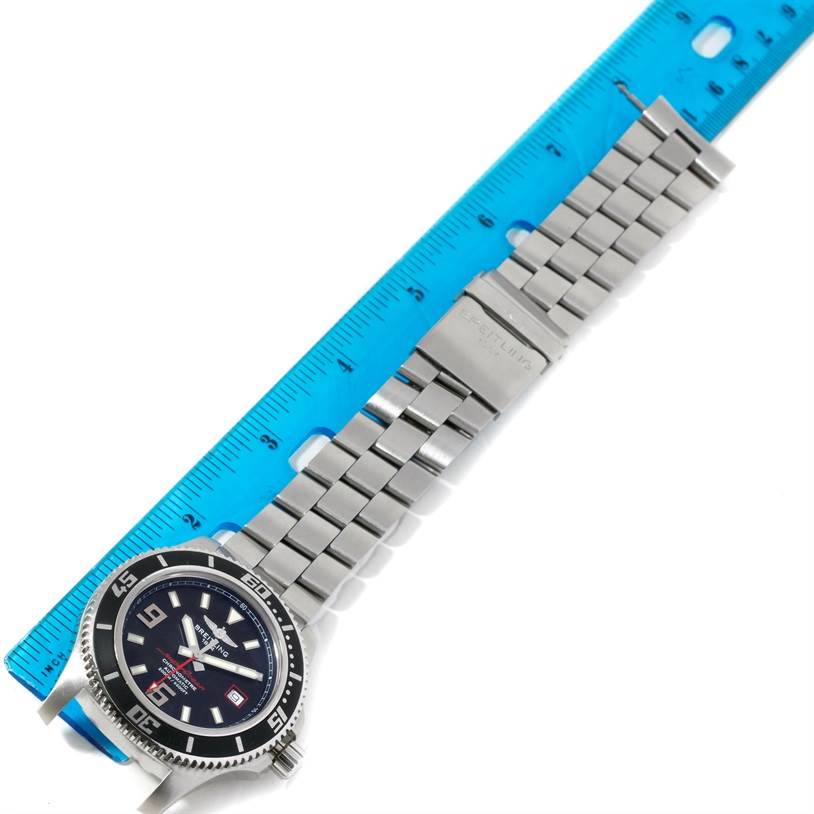 The image shows a top-down view of a Breitling Superocean A17391 Men's Stainless Steel Black Dial A17391 Men's Stainless Steel Black Dial watch with a stainless steel bracelet laid parallel to a blue ruler.