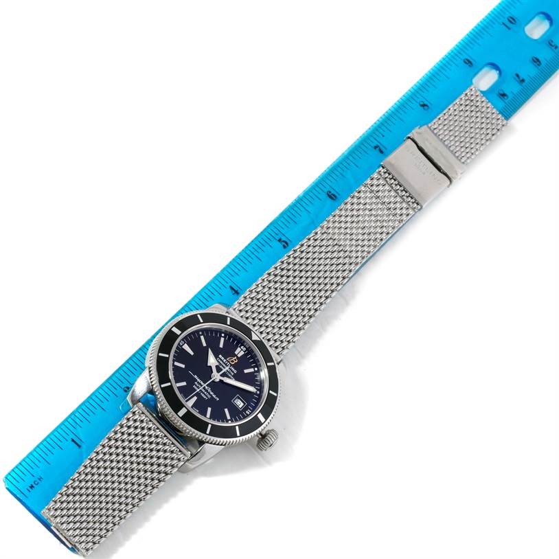 The Breitling Superocean A17320 Men's Stainless Steel Black Dial A17320 Men's Stainless Steel Black Dial watch is shown at an angle, highlighting the mesh strap, dial, and bezel alongside a blue ruler.