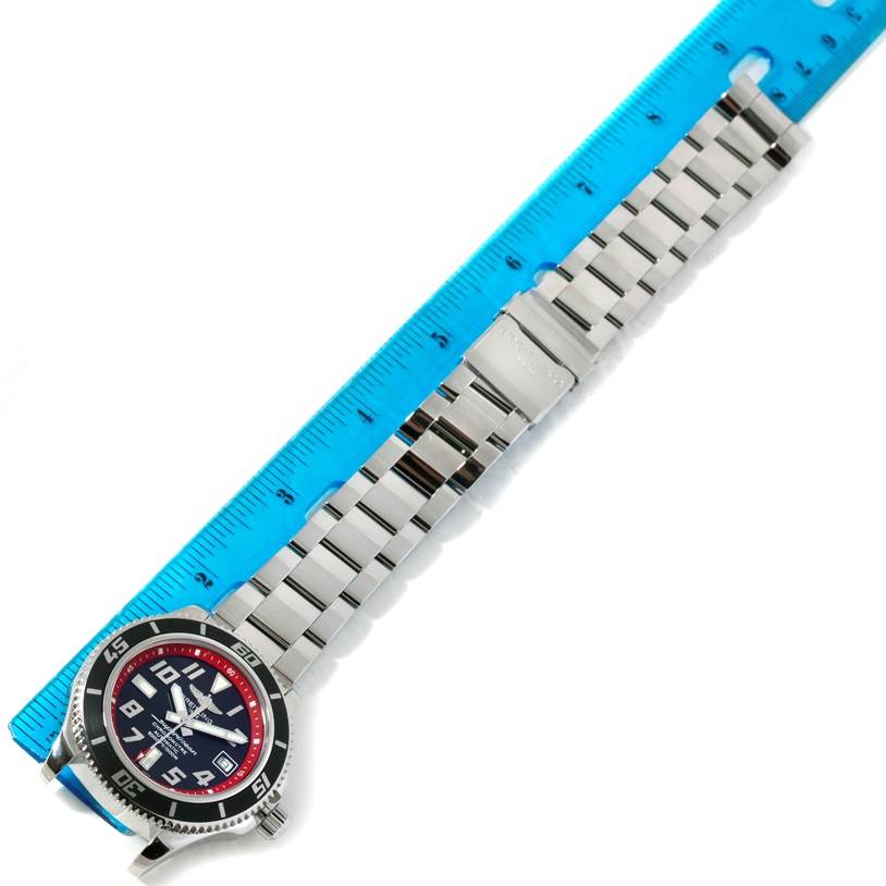 The Breitling Superocean A17364 Men's Stainless Steel Black Dial A17364 Men's Stainless Steel Black Dial watch is shown flat with its stainless steel bracelet extended next to a blue ruler for scale.