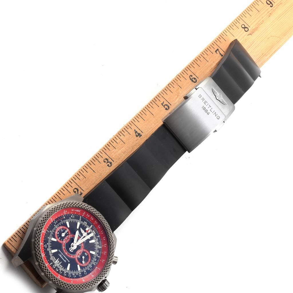 This image shows the Breitling Bentley E27365 Men's Titanium Black Dial E27365 Men's Titanium Black Dial watch face and strap laid next to a ruler for scale.