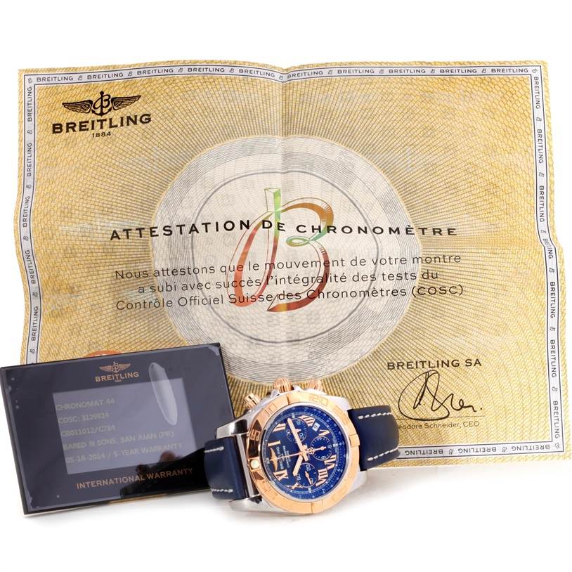 The image shows a Breitling Chronomat CB0110 Men's Steel and Gold (two tone) Blue Dial CB0110 Men's Steel and Gold (two tone) Blue Dial watch with its warranty card and COSC certification document.
