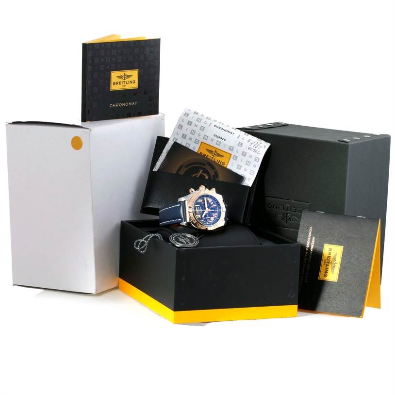 The image shows a Breitling Chronomat CB0110 Men's Steel and Gold (two tone) Blue Dial CB0110 Men's Steel and Gold (two tone) Blue Dial watch with its box, manuals, and accessories, viewed from the front angle.