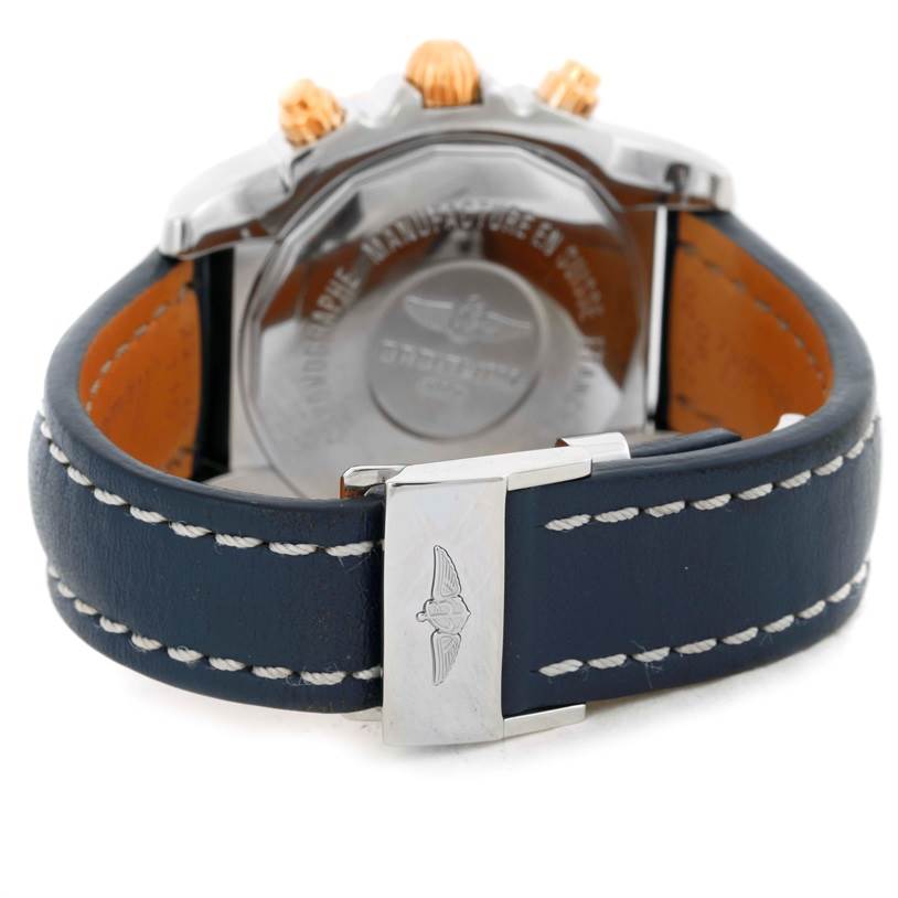 The image shows the back and clasp of a Breitling Chronomat CB0110 Men's Steel and Gold (two tone) Blue Dial CB0110 Men's Steel and Gold (two tone) Blue Dial watch, featuring a blue leather strap with white stitching.