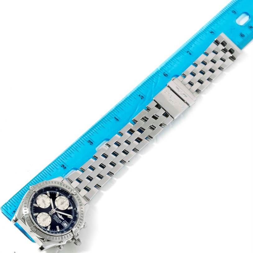 The image shows a top-down view of a Breitling Chronomat A13352 Men's Stainless Steel Black Dial A13352 Men's Stainless Steel Black Dial watch with its bracelet laid next to a blue ruler for scale.