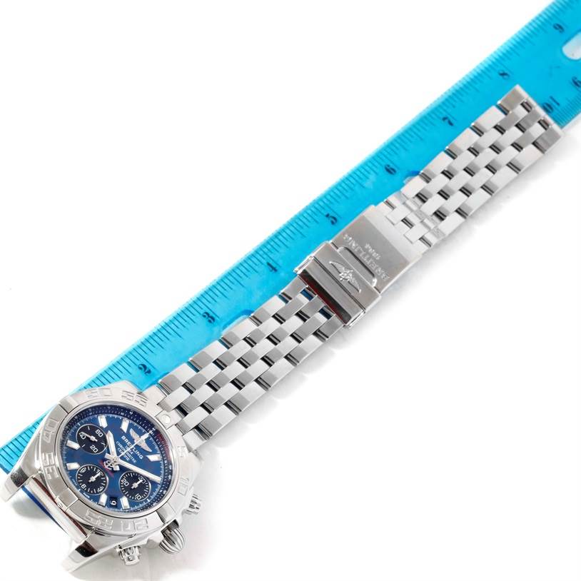 The Breitling Chronomat AB0410 Men
s Stainless Steel Blue Dial AB0410 Men
s Stainless Steel Blue Dial watch is shown from a top-down angle, displaying the face, bracelet, and clasp against a ruler for scale.