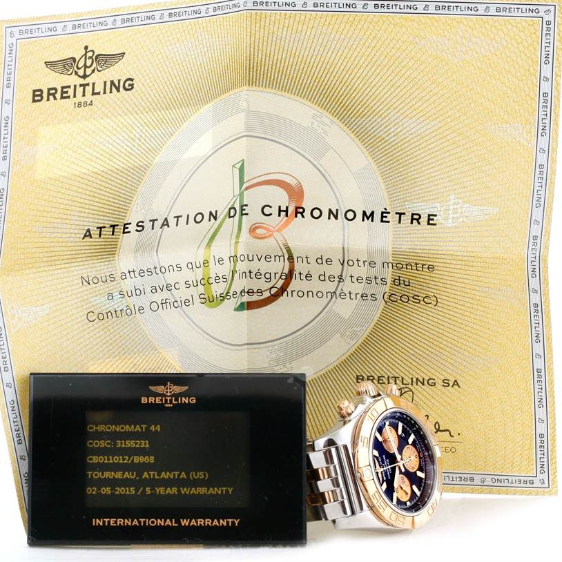 The image shows the Breitling Chronomat CB0110 Men's Steel and Gold (two tone) Black Dial CB0110 Men's Steel and Gold (two tone) Black Dial watch, its warranty card, and COSC certificate from a frontal view.