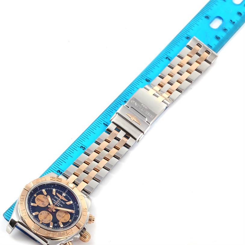 This image shows a top-down view of a Breitling Chronomat CB0110 Men's Steel and Gold (two tone) Black Dial CB0110 Men's Steel and Gold (two tone) Black Dial watch, including its face and full metal bracelet with a ruler for scale.