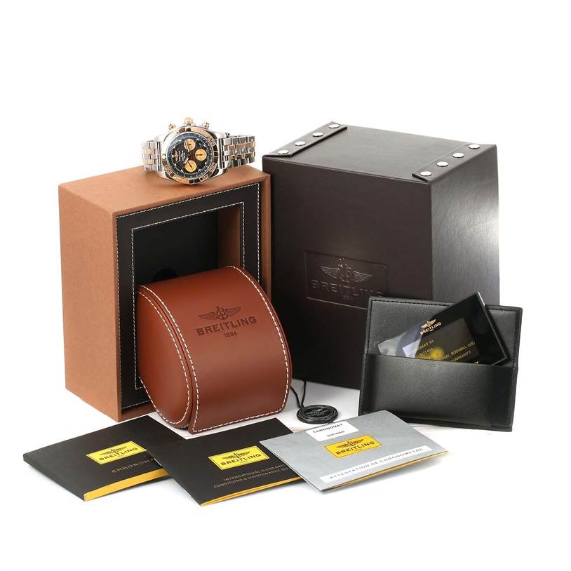 The image shows a Breitling Chronomat CB0110 Men's Steel and Gold (two tone) Black Dial CB0110 Men's Steel and Gold (two tone) Black Dial watch at a slight angle, along with its box, leather case, certificates, and accessories.