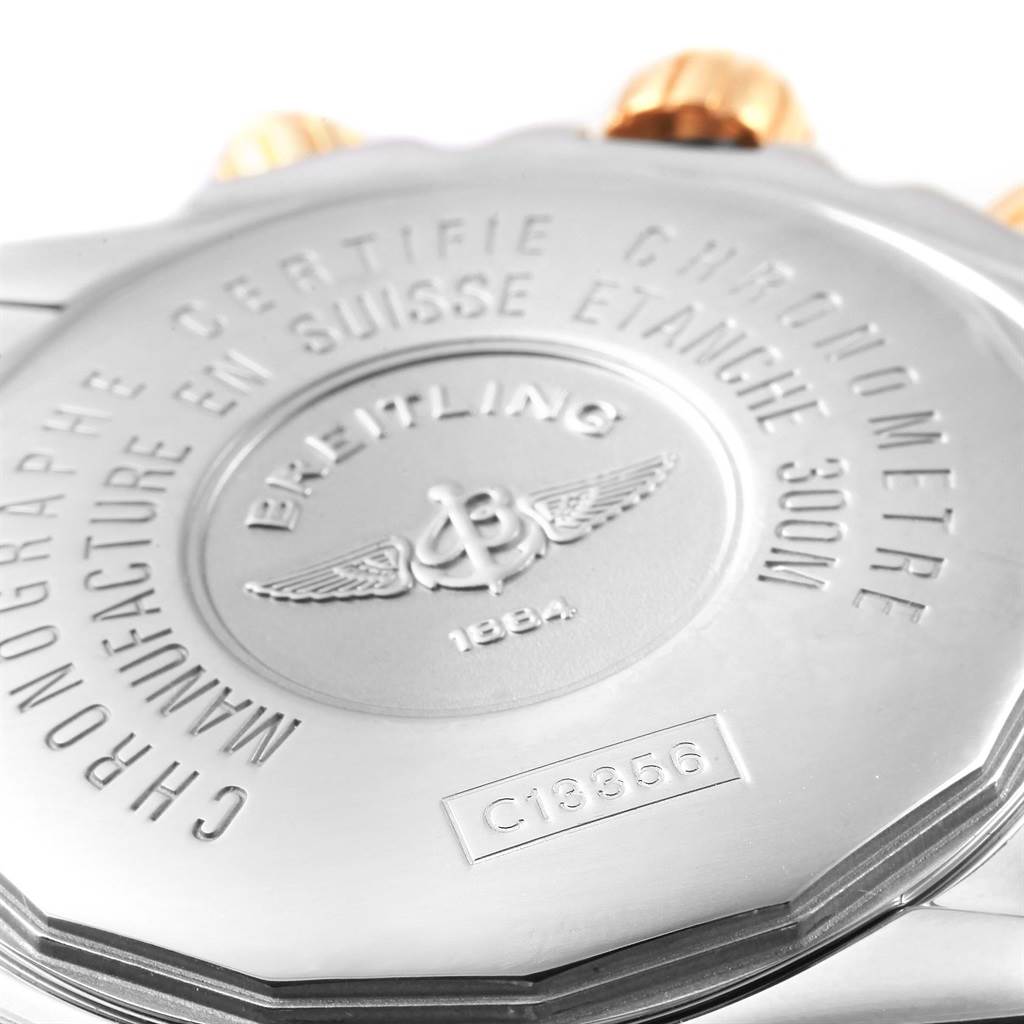 This close-up image shows the case back of a Breitling Chronomat C13356 Men's Steel and Gold (two tone) White Dial C13356 Men's Steel and Gold (two tone) White Dial watch model, featuring engravings and gold accents on the crown.