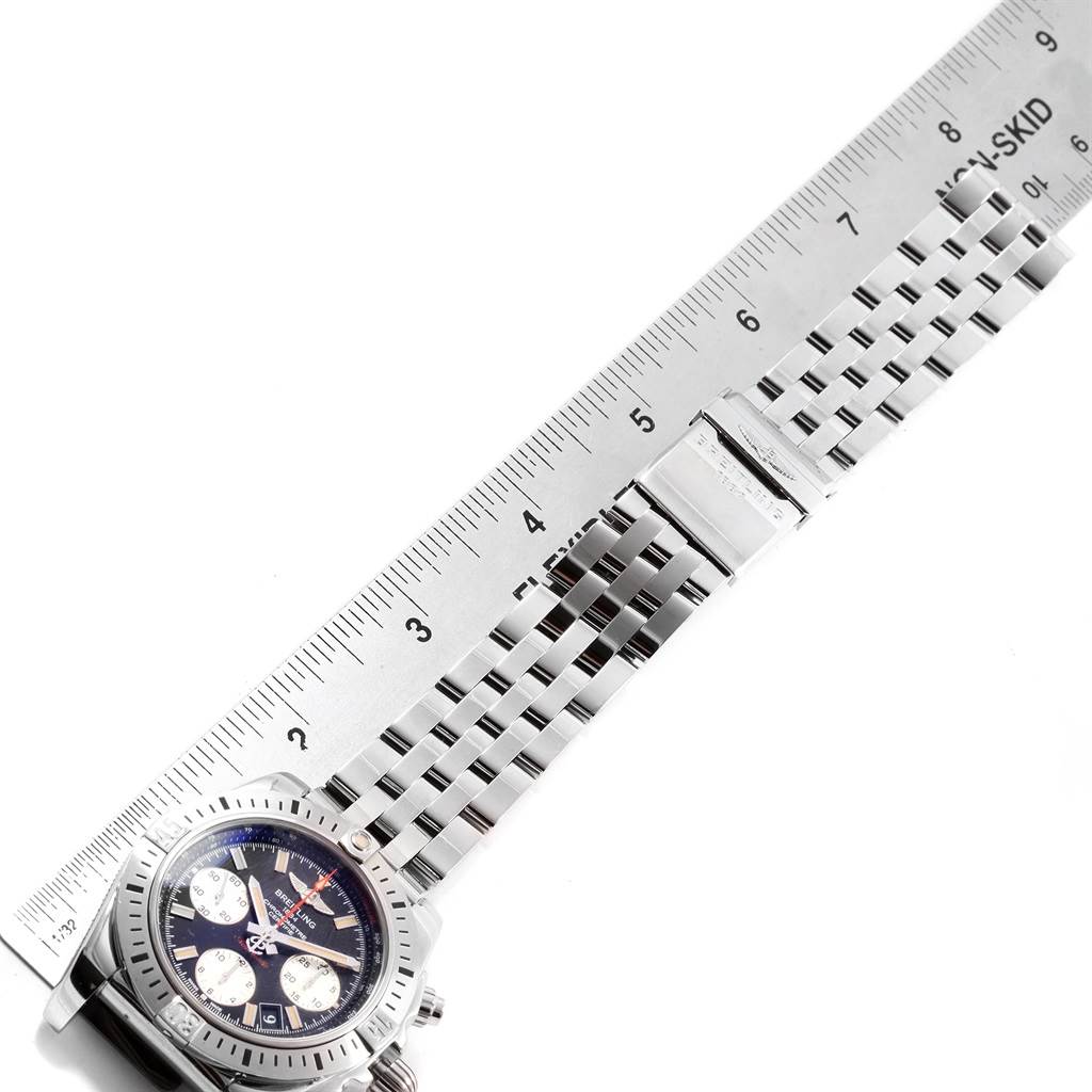 The image shows the Breitling Chronomat AB0114 Men's Stainless Steel Black Dial AB0114 Men's Stainless Steel Black Dial watch at an angle displaying the dial, bezel, and partial bracelet next to a ruler for scale.