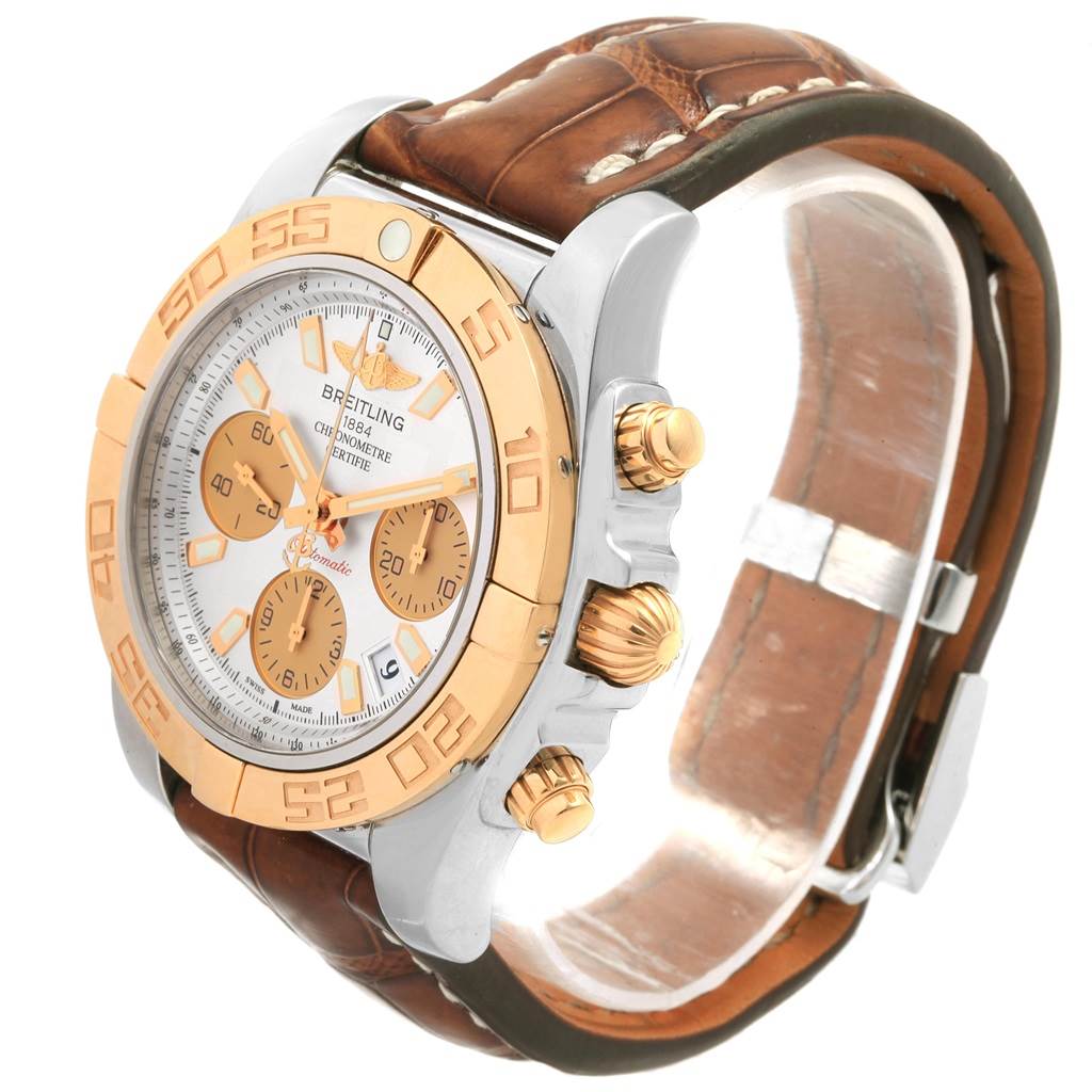 The image shows a Breitling Chronomat CB014012 Men
s Steel and Gold (two tone) Silver Dial CB014012 Men
s Steel and Gold (two tone) Silver Dial watch at an angled side view, highlighting its dial, gold bezel, chronograph buttons, and leather strap.