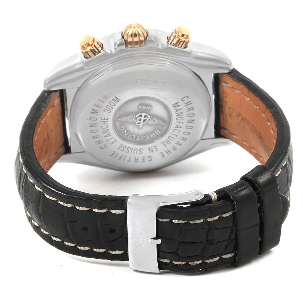 The image shows the back view of a Breitling Chronomat B13356 Men's Steel and Gold (two tone) Black Dial B13356 Men's Steel and Gold (two tone) Black Dial watch and part of its black leather strap with a buckle.
