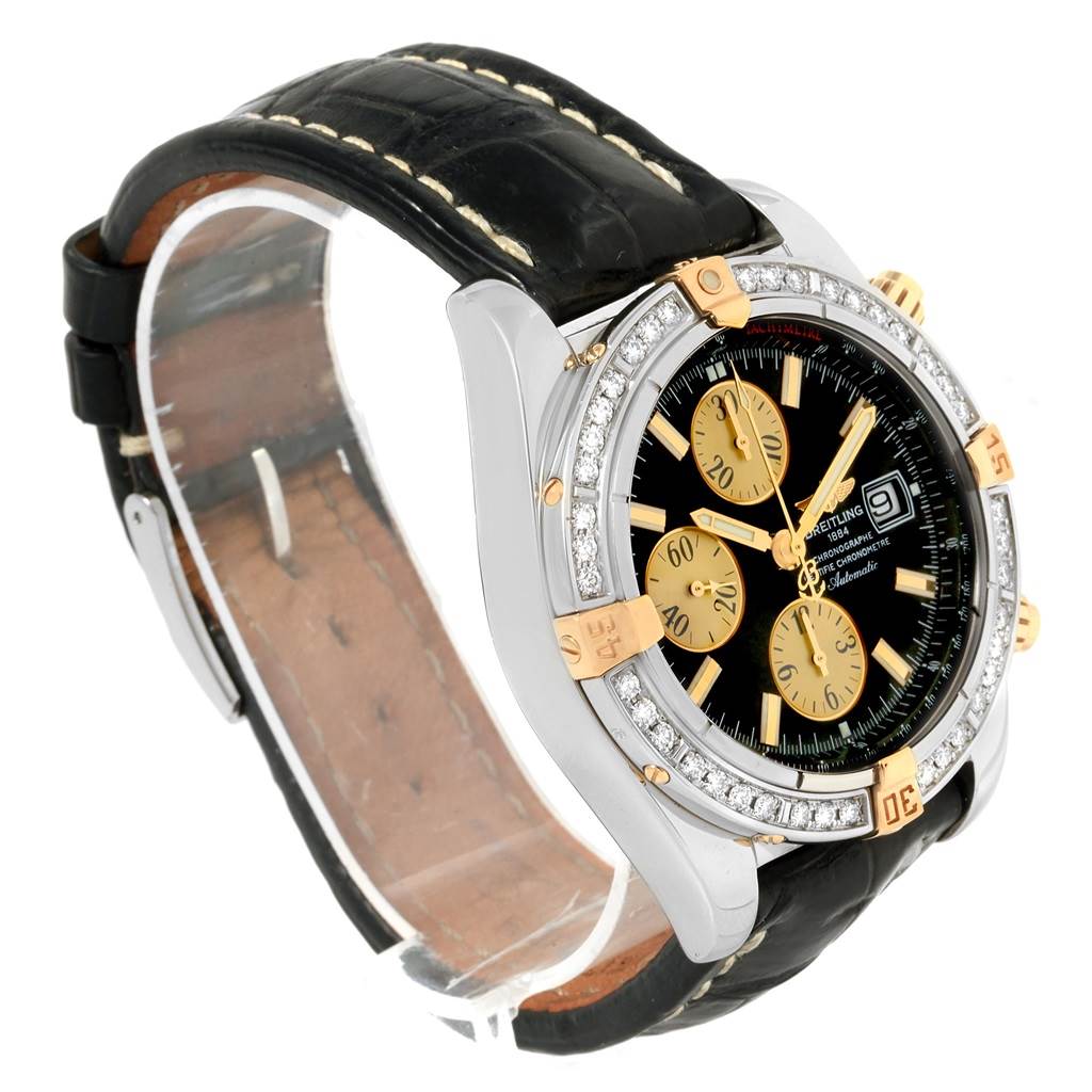 The image shows a side angle view of a Breitling Chronomat B13356 Men's Steel and Gold (two tone) Black Dial B13356 Men's Steel and Gold (two tone) Black Dial watch, highlighting its dial, bezel, and leather strap.