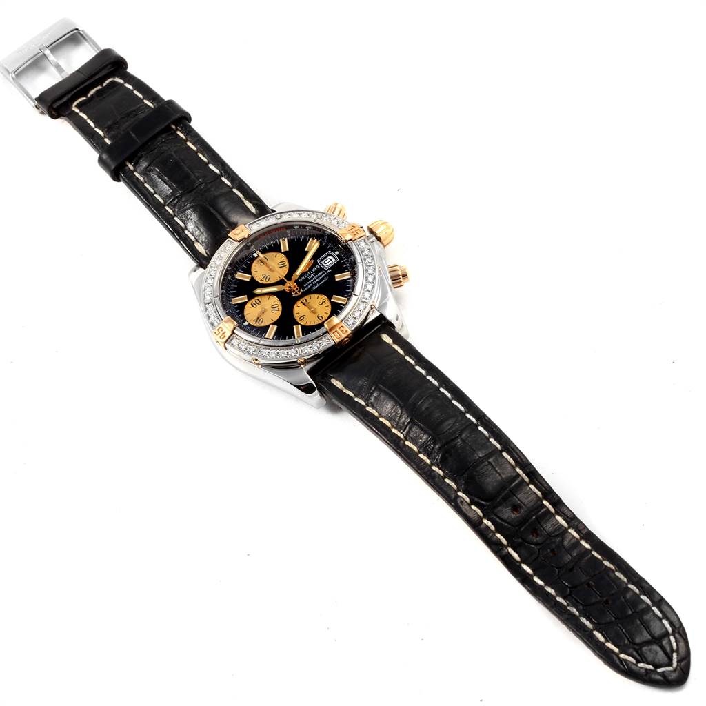 The Breitling Chronomat B13356 Men's Steel and Gold (two tone) Black Dial B13356 Men's Steel and Gold (two tone) Black Dial watch is shown from a top-down angle, including its bezel, dial, and leather strap.