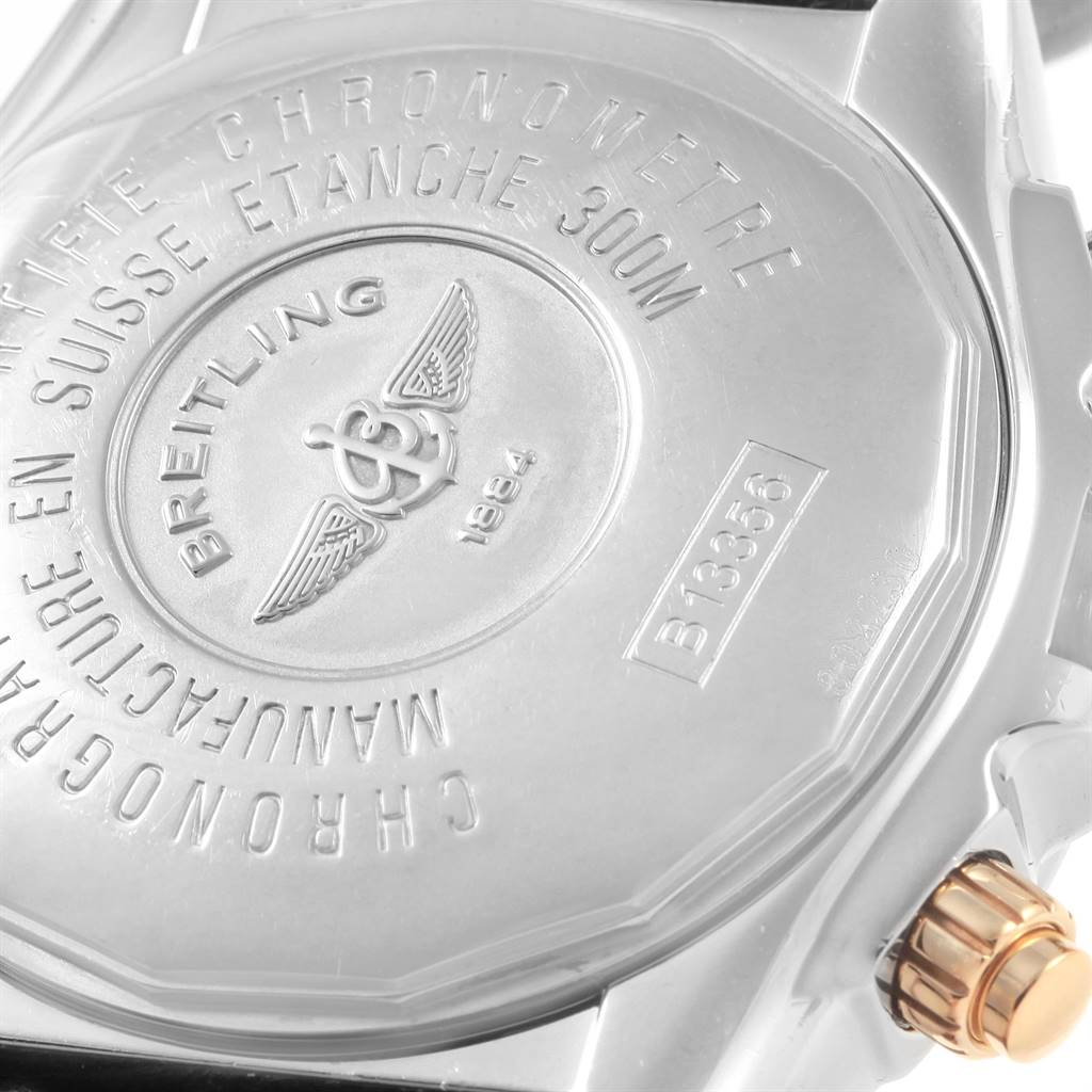 The image shows the back case and part of the crown of a Breitling Chronomat B13356 Men's Steel and Gold (two tone) Black Dial B13356 Men's Steel and Gold (two tone) Black Dial watch.