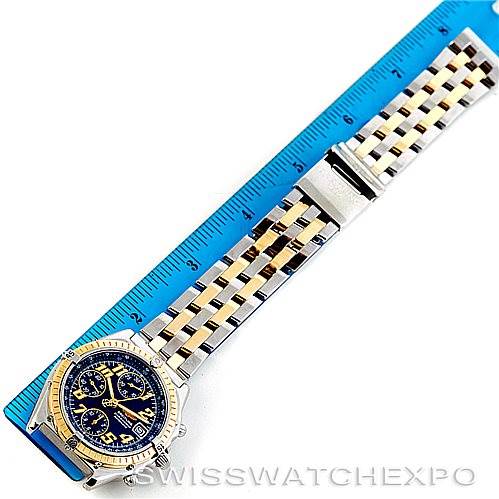 The image shows a Breitling Chronomat D13050 Men's Stainless Steel Blue Dial D13050 Men's Stainless Steel Blue Dial watch with a blue and gold dial, displayed alongside a measuring ruler, showcasing its watchband.