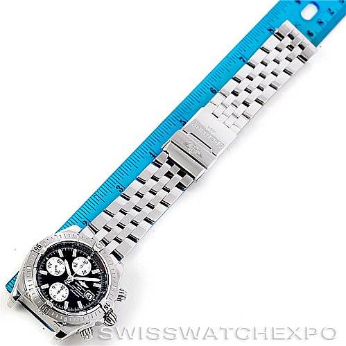The image shows a top-down view of a Breitling Chronomat A13356 Men
s Stainless Steel Black Dial A13356 Men
s Stainless Steel Black Dial watch with its full metal bracelet alongside a blue ruler.