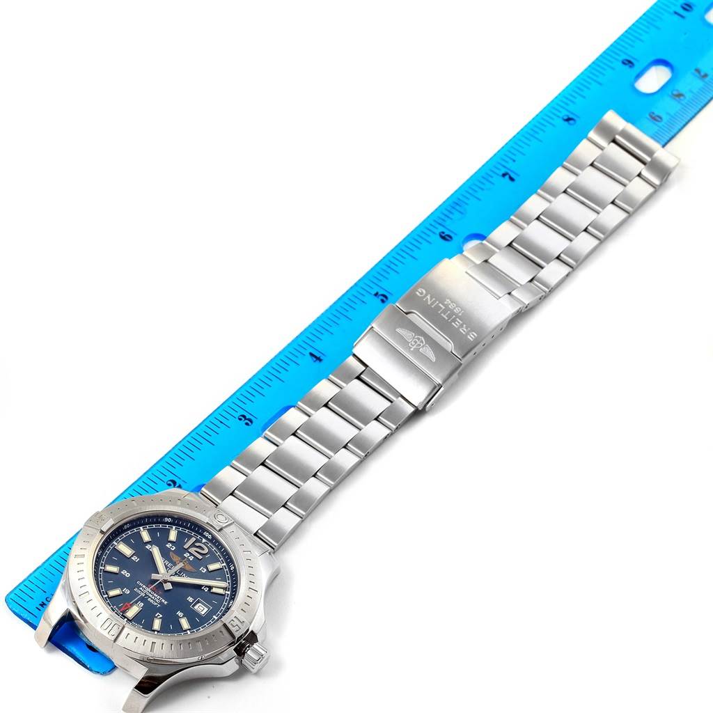 The image shows a Breitling Colt A17388 Men
s Stainless Steel Blue Dial A17388 Men
s Stainless Steel Blue Dial watch with a full metal bracelet, laid flat next to a blue measuring ruler.