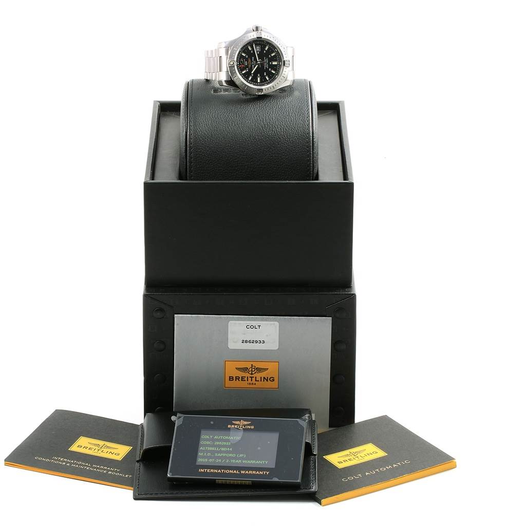 The image shows a Breitling Colt A17388 Men
s Stainless Steel Black Dial A17388 Men
s Stainless Steel Black Dial watch on a stand, with its packaging and warranty documents in front of it.