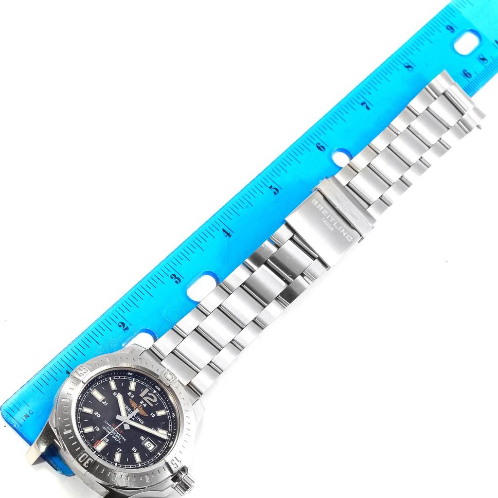 The photo shows a Breitling Colt A17388 Men
s Stainless Steel Black Dial A17388 Men
s Stainless Steel Black Dial watch laid flat next to a ruler, highlighting the watch face and metal band.