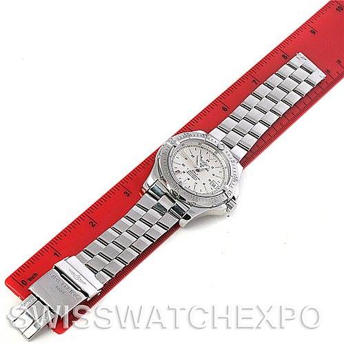 The image shows a Breitling Colt A17380 Men's Stainless Steel White Dial A17380 Men's Stainless Steel White Dial watch laid flat on a red ruler, displaying the face and metal bracelet.