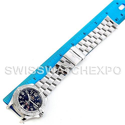 The Colt model by Breitling is shown from an overhead angle, displaying the watch face and full metal bracelet next to a blue ruler.