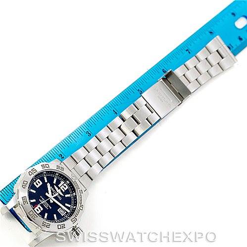 The Breitling Colt A74387 Men
s Stainless Steel Black Dial A74387 Men
s Stainless Steel Black Dial watch is shown from a top-down angle alongside a blue ruler, displaying its face and full metal bracelet.