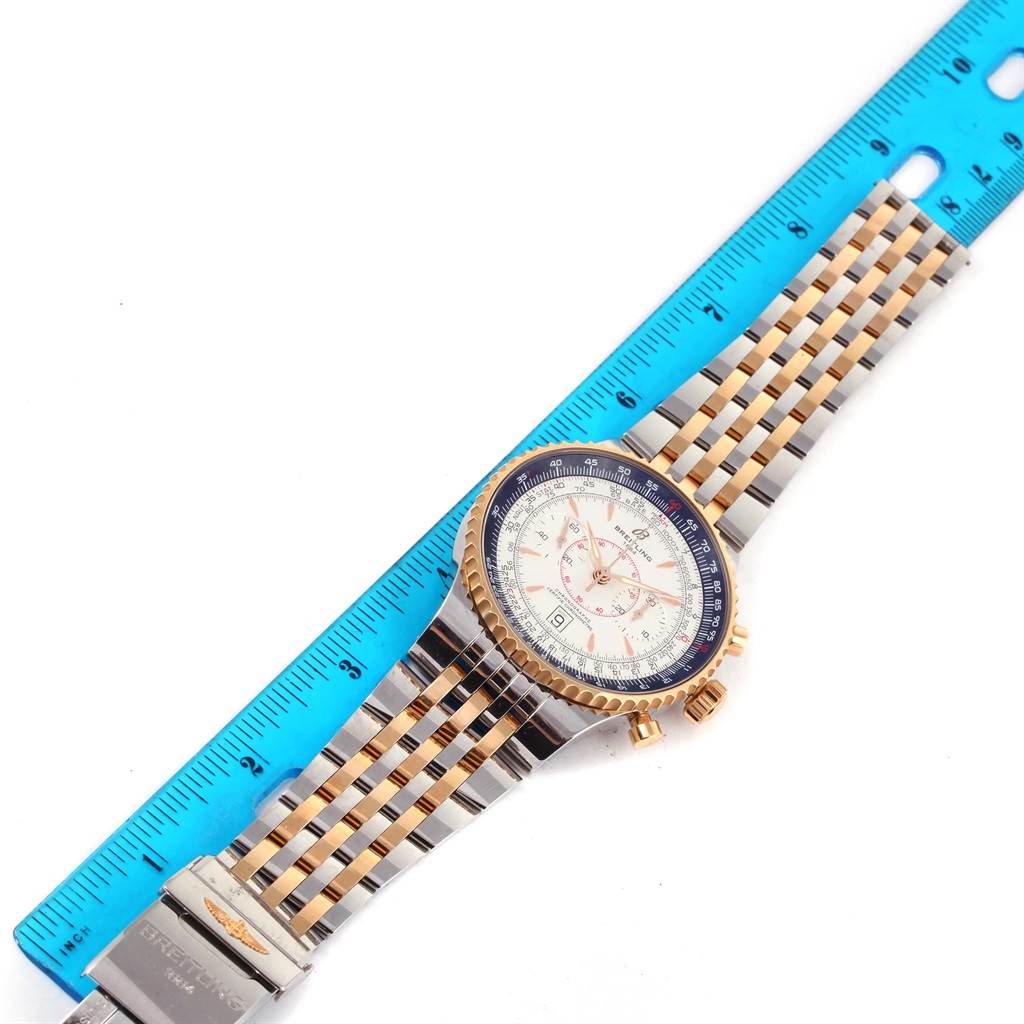 The Breitling Navitimer C23340 Men's Steel and Gold (two tone) Silver Dial C23340 Men's Steel and Gold (two tone) Silver Dial watch is shown flat with its band extended and a ruler beside it, displaying the face, bezel, and clasp.