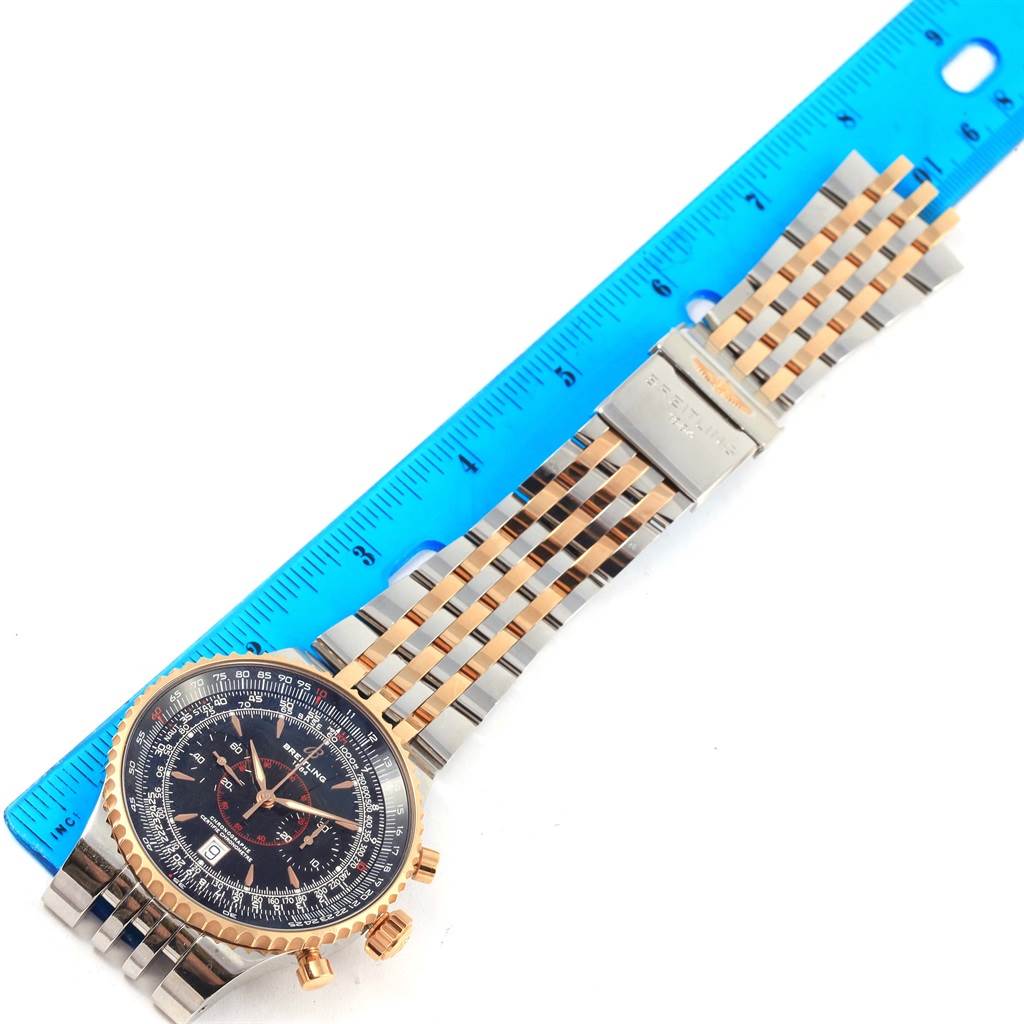 The image shows a top-down view of the Breitling Navitimer C23340 Men
s Steel and Gold (two tone) Black Dial C23340 Men
s Steel and Gold (two tone) Black Dial watch, displaying its face, band, clasp, and a ruler for scale.