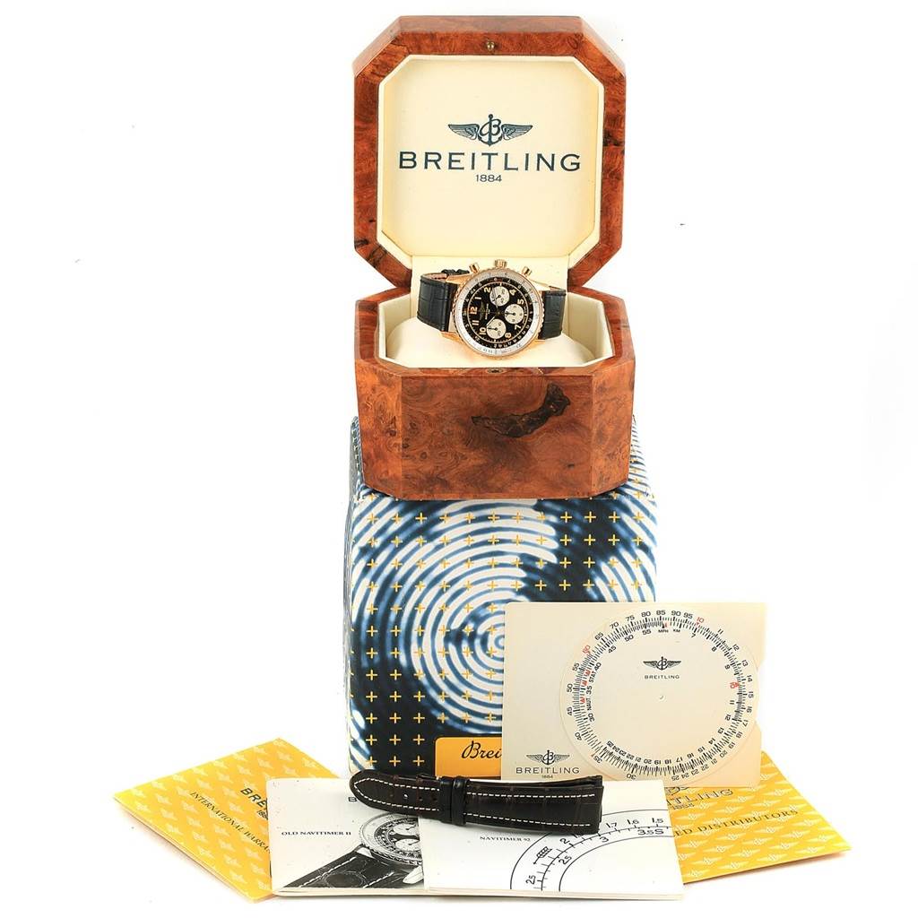 The Breitling Navitimer K30021 Men
s Rose Gold Black Dial K30021 Men
s Rose Gold Black Dial watch is shown in its open display box along with various manuals and a replacement strap at a straight-on angle.