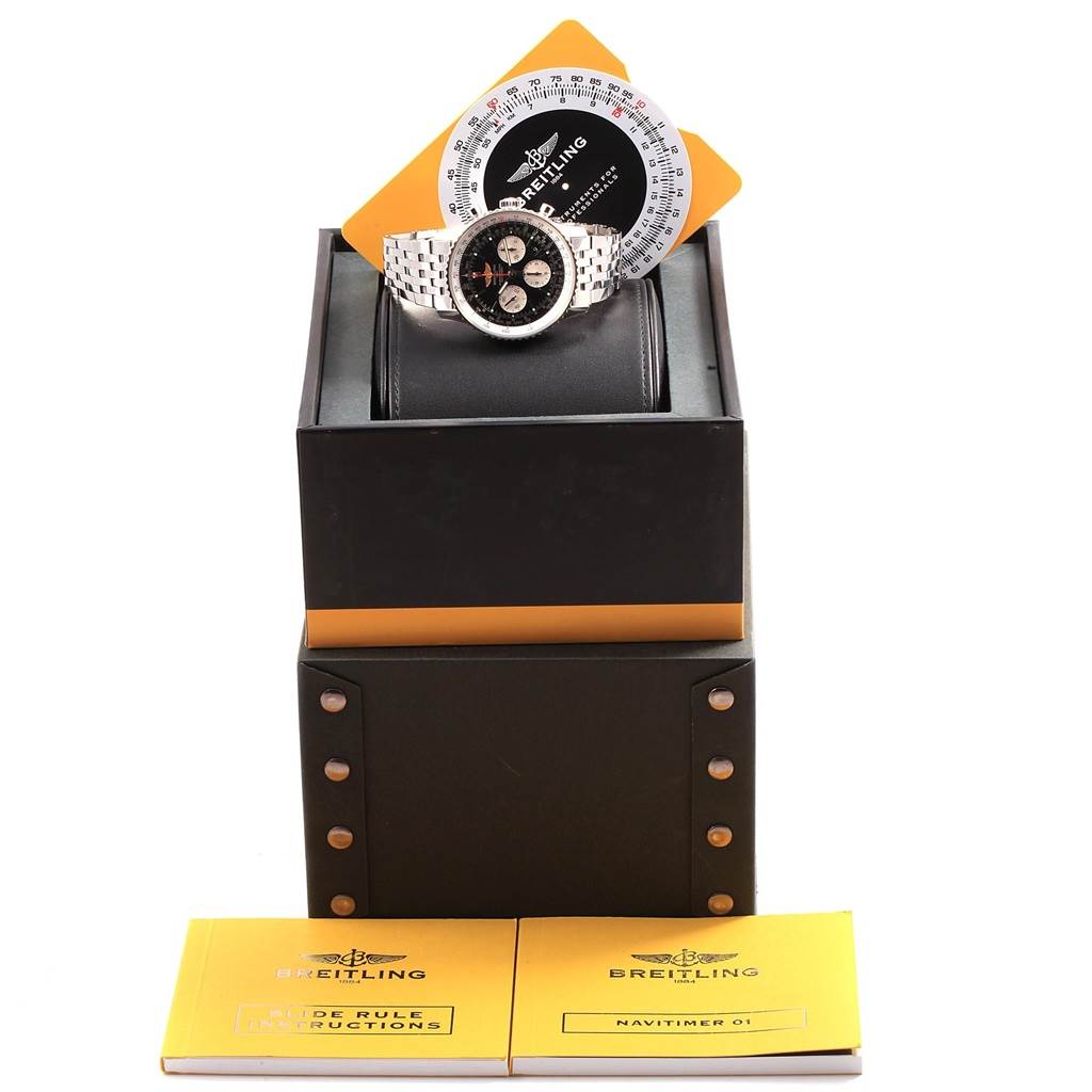 The image shows a Breitling Navitimer AB0120 Men's Stainless Steel Black Dial AB0120 Men's Stainless Steel Black Dial watch with a silver band, placed on a black presentation box, with instruction booklets and a circular slide rule module.
