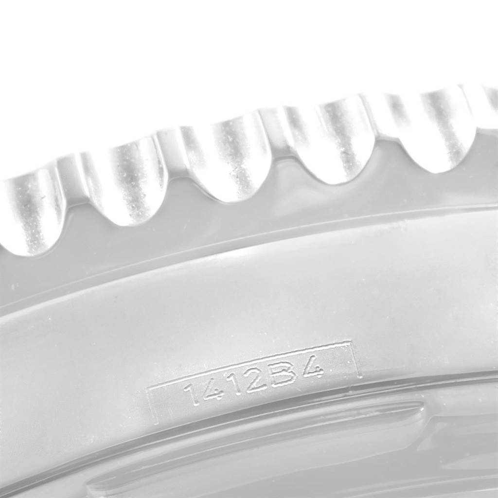 The image shows a close-up of the bezel from a Breitling Navitimer AB0123 Men's Stainless Steel Silver Dial AB0123 Men's Stainless Steel Silver Dial watch model, highlighting its serrated edge and part of a serial number.