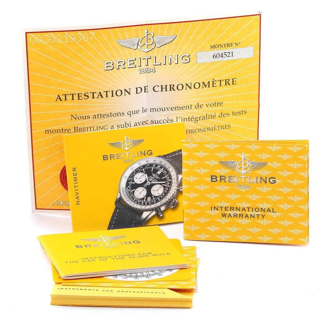 The image shows yellow documents and booklets related to the Breitling Navitimer A23322 Men's Stainless Steel Blue Dial A23322 Men's Stainless Steel Blue Dial watch, including warranty and chronometer certification.