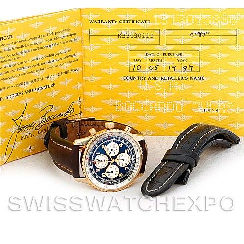 The image shows a Breitling Navitimer K33030 Men's Yellow Gold Blue Dial K33030 Men's Yellow Gold Blue Dial watch, an extra strap, and its warranty certificate viewed from an angled perspective.