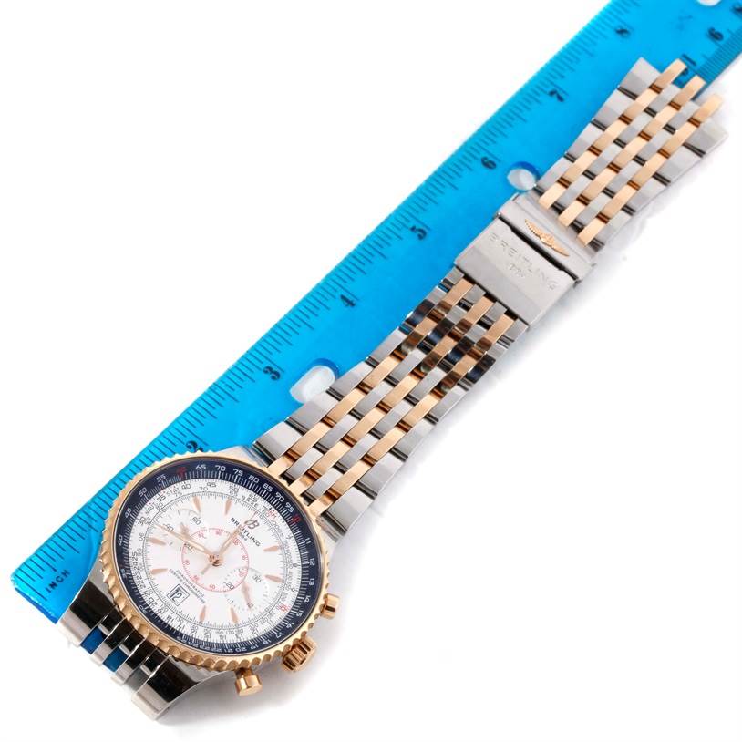 The Navitimer model by Breitling is shown from an overhead angle, highlighting the watch face, bezel, and metal bracelet alongside a ruler.