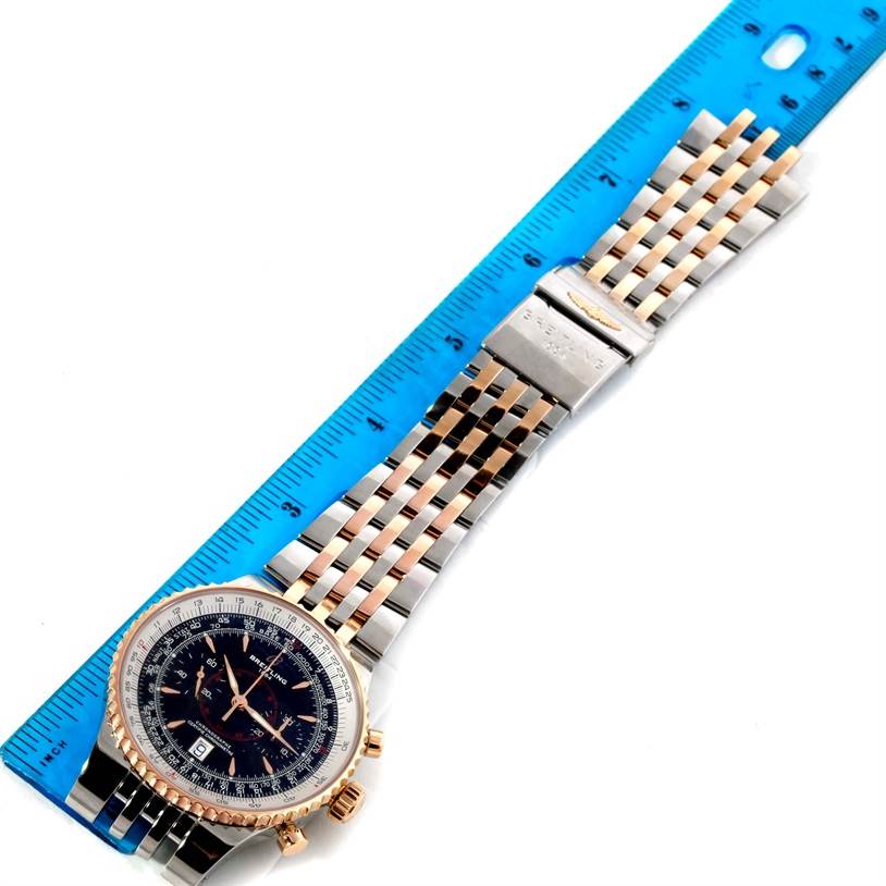 The Breitling Navitimer C23340 Men
s Steel and Gold (two tone) Black Dial C23340 Men
s Steel and Gold (two tone) Black Dial watch is shown from a top-down angle, displaying its face, bracelet, and clasp, next to a ruler.